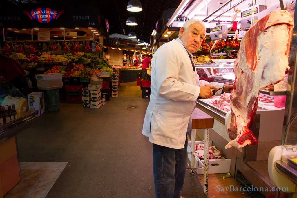 Eeen beenhouwer die vlees versnijd op de La Boqueria markt in Barcelona